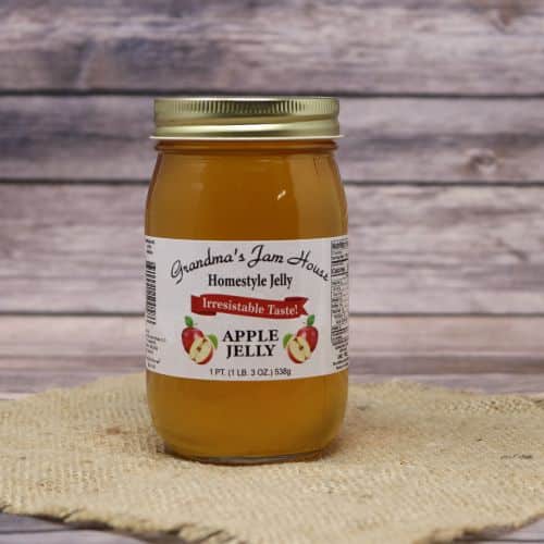 An 18oz glass jar of Grandma's Jam House Apple Jelly, on rustic burlap with a wooden background.