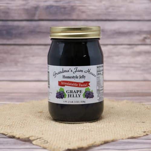 An 18oz glass jar of Grandma's Jam House Grape Jelly, on rustic burlap with a wooden background.