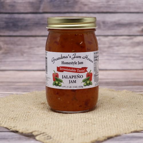 An 18oz glass jar of Grandma's Jam House Jalapeno Jam, on rustic burlap with a wooden background.