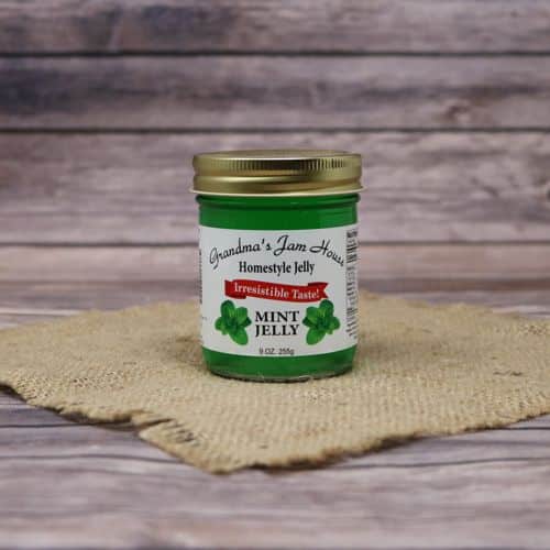 A 9oz glass jar of Grandma's Jam House Mint Jelly, on rustic burlap with a wooden background.