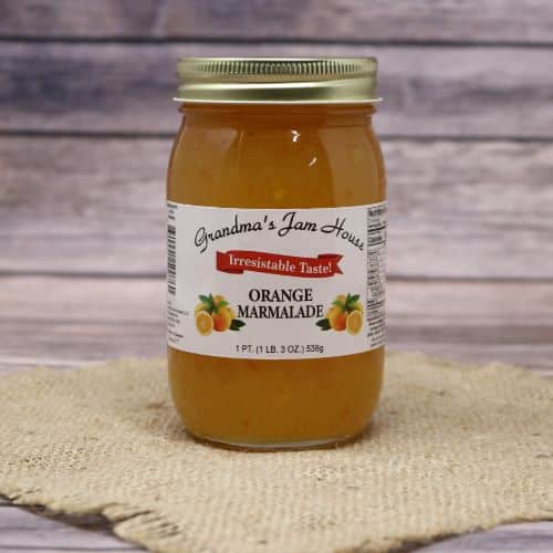 An 18oz glass jar of Grandma's Jam House Orange Marmalade, on rustic burlap with a wooden background.