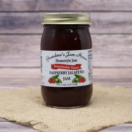 An 18oz glass jar of Grandmas Jam House Raspberry Jalapeno Jam, on rustic burlap with a wooden background.