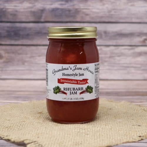 An 18oz glass jar of Grandma's Jam House Rhubarb Jam, on rustic burlap with a wooden background.