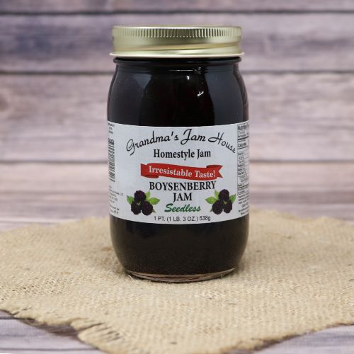 An 18oz glass jar of Grandma's Jam House Seedless Boysenberry Jam, on rustic burlap with a wooden background.