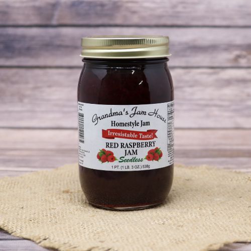 An 18oz glass jar of Grandma's Jam House Seedless Red Raspberry Jam, on rustic burlap with a wooden background.