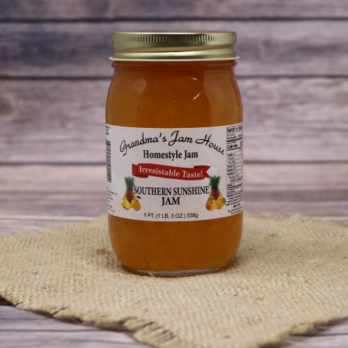 An 18oz glass jar of Grandma's Jam House Southern Sunshine Jam, on rustic burlap with a wooden background.