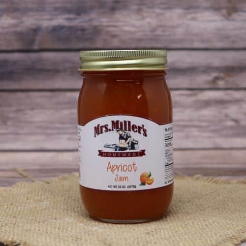 A 20oz glass jar of Mrs. Miller's Apricot Jam, on rustic burlap with a wooden background.