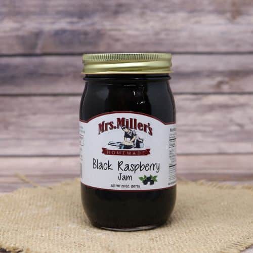 A 20oz glass jar of Mrs. Miller's Black Raspberry Jam, on rustic burlap with a wooden background.