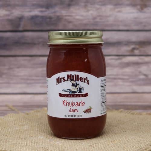 A 20oz glass jar of Mrs. Miller's Rhubarb Jam, on rustic burlap with a wooden background.