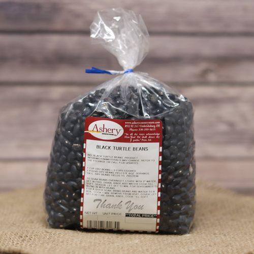 A bag of Black Turtle Beans, sealed with a twist tea, on rustic burlap and a wooden background.