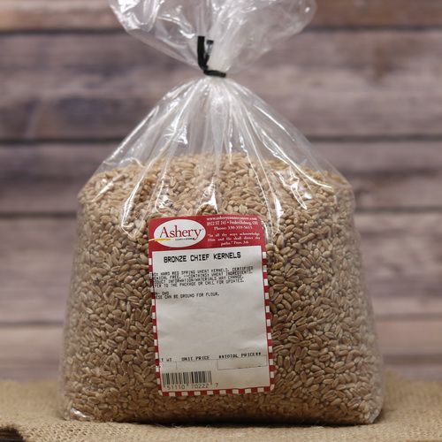 A bag of Bronze Chief Kernels, sealed with a twist tie, on rustic burlap with a wooden background.