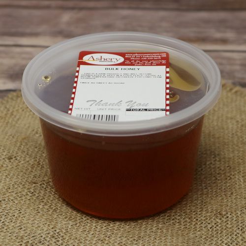 A round container of Raw Honey, on rustic burlap with a wooden background.