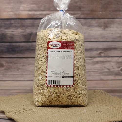 A bag of Gluten Free Regular Rolled Oats, sealed with a twist tie, on rustic burlap with a wooden background.