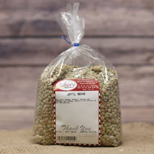 A clear bag of dried Lentil Beans sealed with a blue twist tie on rustic burlap and wooden background.