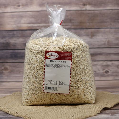 A bag of Organic Quick Oats, sealed with a twist tie, on rustic burlap with a wooden background.