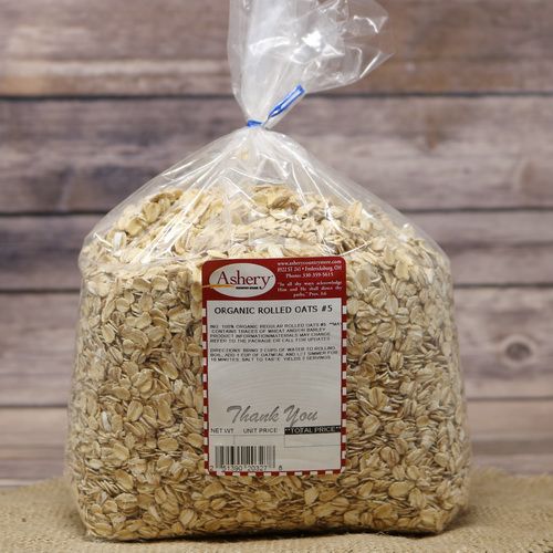 A bag of Organic Rolled Oats, sealed with a twist tie, on rustic burlap with a wooden background.