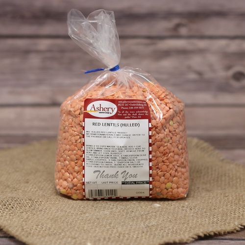 A bag of hulled Red Lentils sealed with a twist tie on rustic burlap with a wooden background.