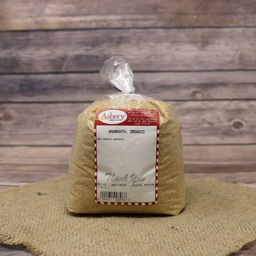 A bag of Stutzman Farms Organic Amaranth, closed with a twist tie, on rustic burlap with a wooden background.