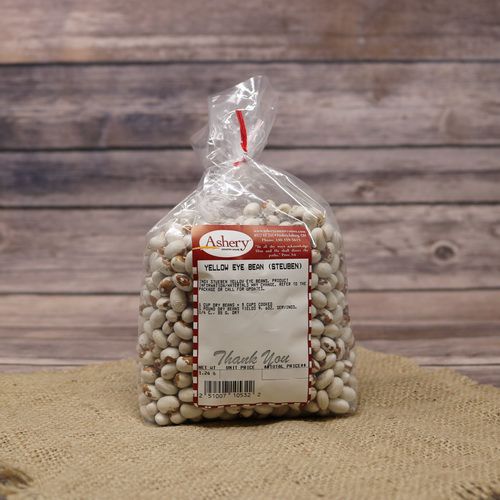 A clear plastic bag of dried Yellow-Eye-Stueben-Beans on rustic burlap with a wooden background.