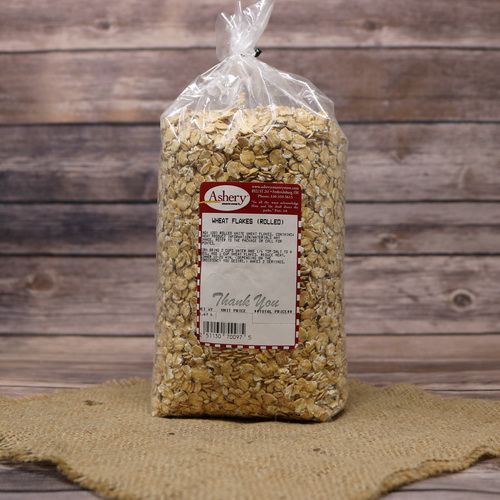 A bag of Wheat Flakes, sealed with a twist tie, on rustic burlap with a wooden background.