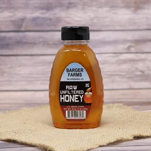 A 1lb bottle of Barger's Clover Honey, on rustic burlap with a wooden background.