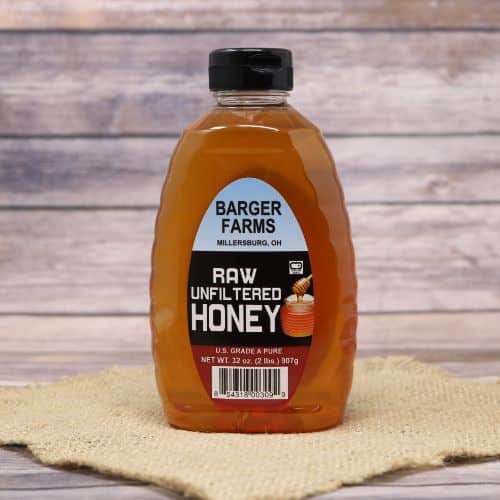 A 2lb bottle of Barger's Clover Honey, on rustic burlap with a wooden background.