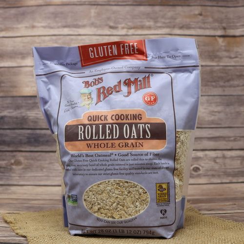 A bag of Bob's Red Mill Gluten Free Quick Cooking Oats on rustic burlap with a wooden background.