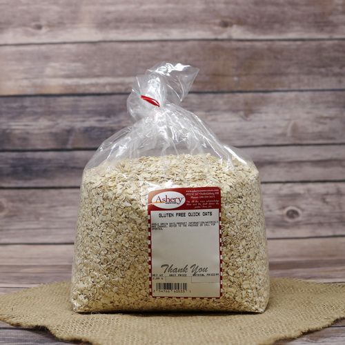 A bag of Gluten Free Quick Oats, sealed with a twist tie, on rustic burlap with a wooden background.