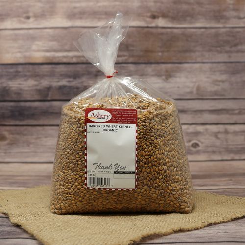 A bag of Hard Red Wheat Kernels Organic, sealed with a twist tie, on rustic burlap with a wooden background.