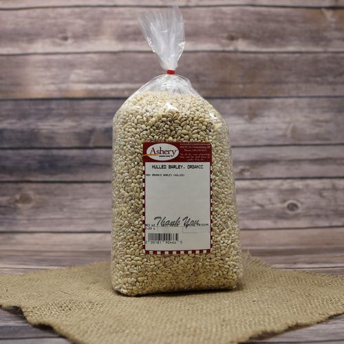 A bag of Organic Hulled Barley, sealed with a twist tie, on rustic burlap with a wooden background.