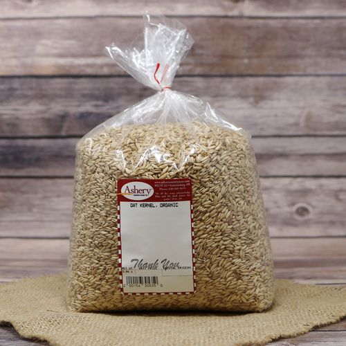 A bag of Organic Oat Kernels, sealed with a twist tie, on rustic burlap with a wooden background.