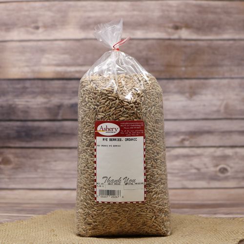 A bag of Organic Rye Berries, sealed with a twist tie, on rustic burlap with a wooden background.