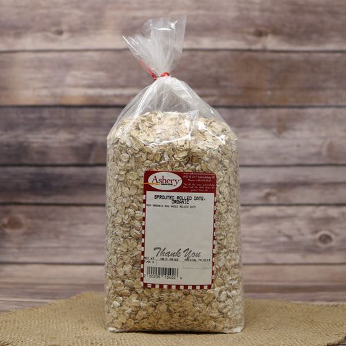 A bag of Sprouted Rolled Oats Organic, sealed with a twist tie, on rustic burlap with a wooden background.