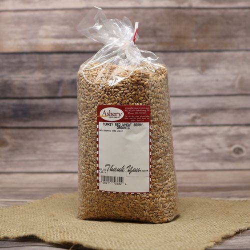 A bag of Turkey Red Wheat Berries Organic, sealed with a twist tie, on rustic burlap with a wooden background.