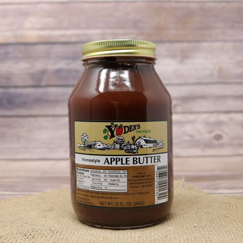 A 32oz glass jar of Yoder's Fine Foods Apple Butter, on rustic burlap with a wooden background.