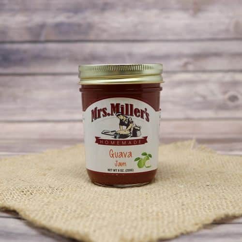 A 9oz glass jar of Mrs. Miller's Homemade Guava Jam, on rustic burlap with a wooden background.