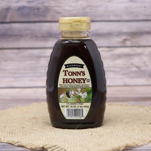 A bottle of Tonn's Buckwheat Honey, on rustic burlap with a wooden background.