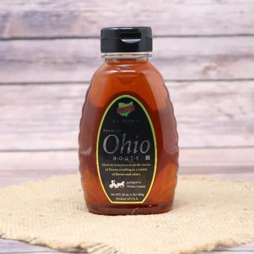 A bottle of Premium Ohio Honey, on rustic burlap with a wooden background.