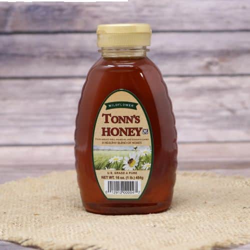 A bottle of Tonn's Wildflower Honey, on rustic burlap with a wooden background.