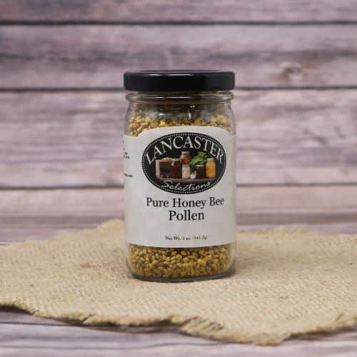 A glass jar of Lancaster Bee Pollen, on rustic burlap with a wooden background.