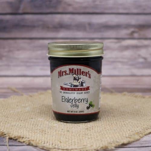 A 9oz glass jar of Mrs. Miller's Elderberry Jelly with no sugar added, on rustic burlap with a wooden background.