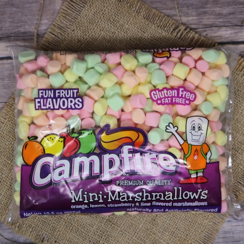 Bag of Campfire Mini-Marshmallows in assorted fruit flavors, gluten-free, displayed on burlap with a wood background.