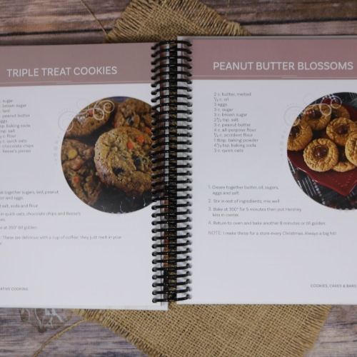 Open pages of the "Creative Cooking: Recipes from Five Amish Sisters" cookbook featuring recipes for Triple Treat Cookies and Peanut Butter Blossoms.