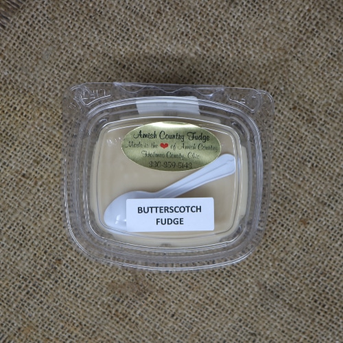 A Container of Butterscotch Fudge Amish Country with a small spoon on a burlap bag.