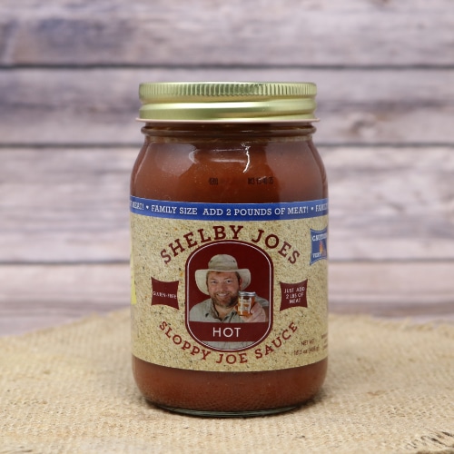 A jar of Sloppy Joe Sauce Hot on rustic burlap and a wooden background.