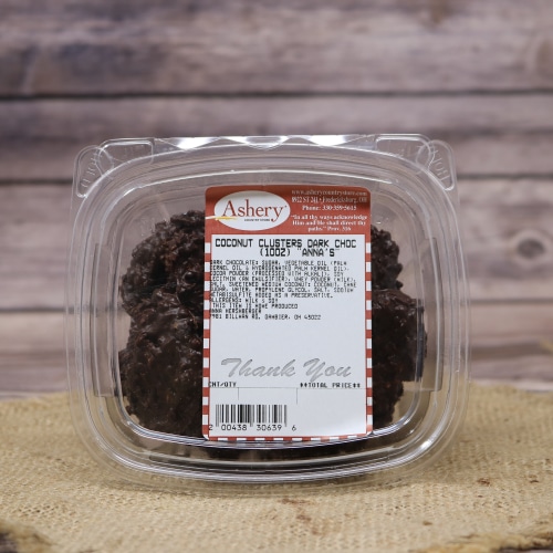 A clear plastic container of Coconut Clusters Dark Chocolate on a rustic burlap with a wooden background.