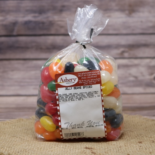 A clear plastic bag with Jelly Beans Spiced that are different colors sealed with black twist tie on rustic burlap with a wooden background.