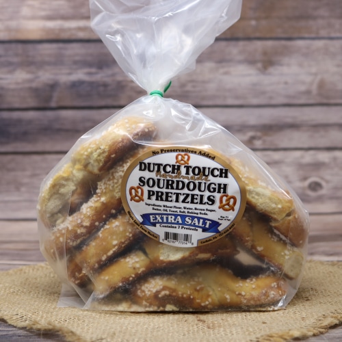 A clear bag of seven Sourdough Pretzels Extra Salt, on rustic burlap with a wooden background.