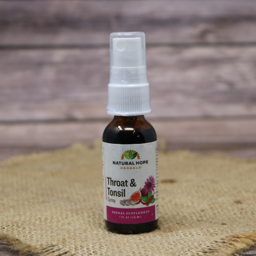 A glass spray bottle of Throat and Tonsil Spray by Natural Hope Herbals on rustic burlap with a wooden background.